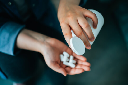 White tablets or pills or dietary supplements in girl hand. Drug addiction on painkillers. Treatment of diseases at home.