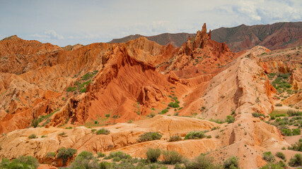 Dramatic clouds and blue sky over red sandy canyons in Kyrgyzstan.Unusual geological landscape.