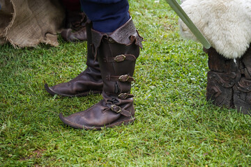  Legs of a man in medieval leather boots on the grass 