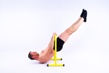 Young muscular man doing parallel bar exercises in dark white red studio with copy space
