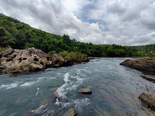 Mesmerising wild lake view , flowing water surrounded by rocks under the cloudy sky , from Bedoor Forest Lake Kerala