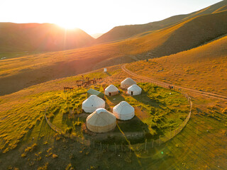 Yurts in Kyrgyzstan nature, simple buildings alone in the middle of nowhere during sunset or sunrise. Panorama landscape of the mountain valley. - obrazy, fototapety, plakaty
