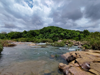 Mesmerising wild lake view , flowing water surrounded by rocks under the cloudy sky , from Bedoor Forest Lake Kerala
