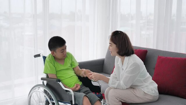Loving Care, holding hand, Amidst encouragement and coexistence, a mother provides unwavering care to her disabled son in a wheelchair, an 11-year-old boy. Slow motion shot