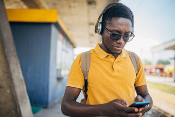 Young man with headphones and mobile phone on the train station