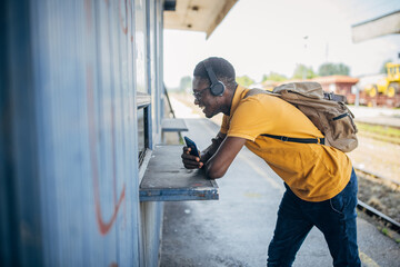 Young man with headphones and mobile phone on the train station