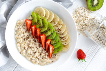 Organic gluten free oatmeal with fresh fruits, strawberry, banana, kiwi and flax seeds. Recipe of energy breakfast, fitness food. Balanced nutrition full of vitamins and Omega-3 fatty acids.