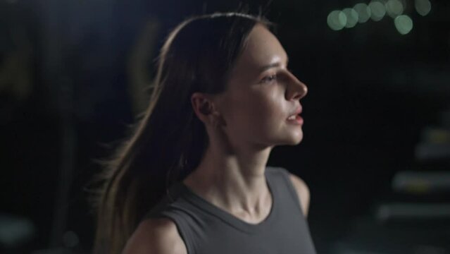 Young woman athlete run on a treadmill, aerobic exercise and endurance training, portrait, a runner trains in the gym, 4k slow motion.