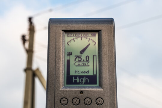 The measuring device shows a high level of electric field strength near a high-voltage power line