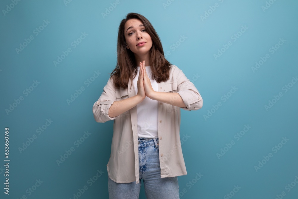 Wall mural European model appearance young dark-haired lady in informal clothes posing against a blue background