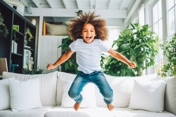 Happy energetic african american children jumping on sofa.