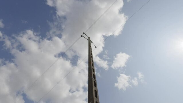 Clouds pass above french utility pole made of light weight concrete cinderblocks