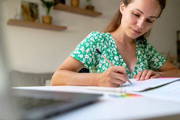 Adult woman student writing exercise in student's workbook, self-education, home education.