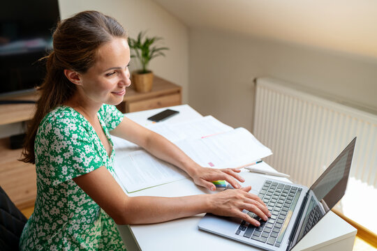 Young adult woman studying online on the Internet using her laptop for the e-learning, online courses and educational training.