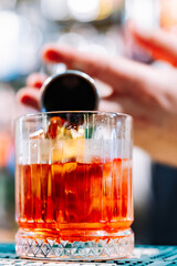 man bartender hand making negroni cocktail. Negroni classic cocktail and gin short drink with sweet vermouth, red bitter liqueur
