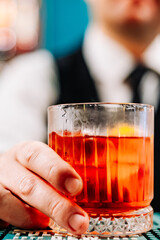 man bartender hand making negroni cocktail. Negroni classic cocktail and gin short drink with sweet vermouth, red bitter liqueur
