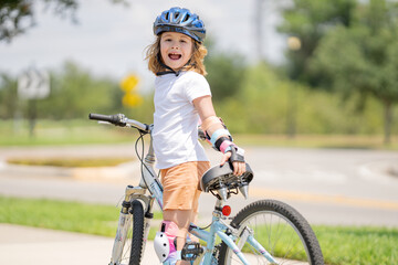 Kid riding bike in a helmet. Child with a childs bike and in protective helmet. Happy kid boy having fun in summer park with a bicycle. Bike helmet, bicycle safety, cycling accessories.