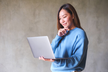Portrait image of a businesswoman holding and working on laptop computer