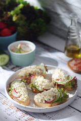 A plate with sandwiches with cottage cheese, radish and cucumber in rustic style	