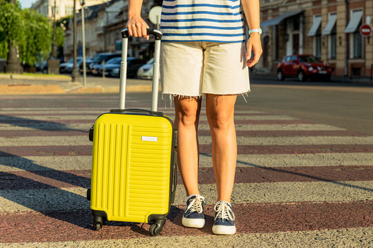 Woman with yellow suitcase on road in the city