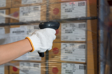 Hand of warehouse worker scanning barcodes on boxes on shelves pallet in storage warehouse. Worker working and holding barcodes in warehouse