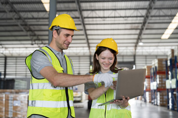 Group of male and female warehouse worker in safety vest and helmet working with laptop computer in...