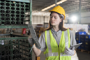 Female warehouse worker wearing safety uniform working and inspecting quality for auto spare parts...