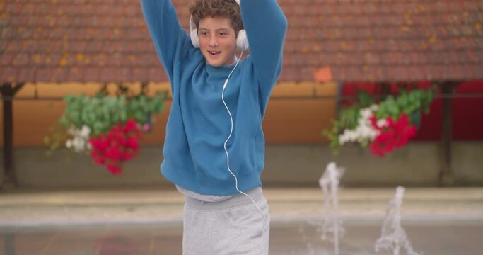 Dancing teenager with headphones listening to music performing various freestyle dance outdoors having fun. Modern lifestyle, happiness concept. breakdancing, hiphop dancing, street dancing