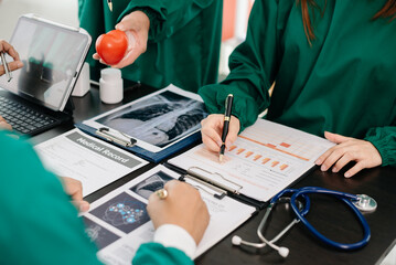 Medical team having a meeting with doctors in white lab coats and surgical scrubs seated at a table...