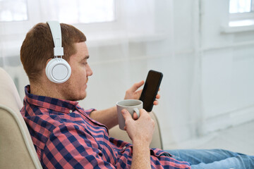 Weekend Vibes: Young Redhead Engrossed in Music and Podcasts on His Smartphone. Rise of Online Audio Content: Exploring the World of Podcasts and Music App