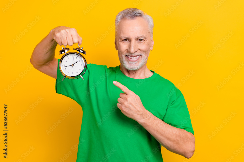 Sticker Portrait of positive friendly person direct finger arm hold retro classic bell ring clock isolated on yellow color background