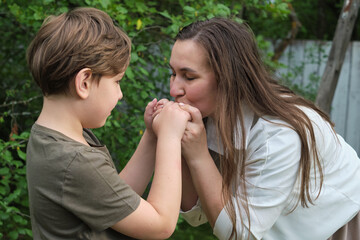 An endearing scene of a mother and son sharing a joke and a hug in a serene garden, highlighting the beauty of natural parent-child connection
