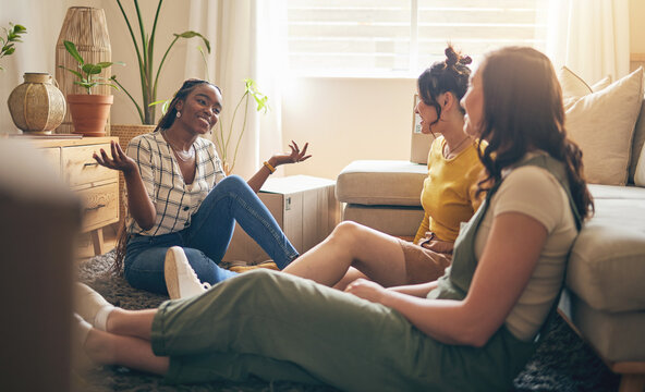 Happy, gossip and friends on a floor relax, talking and bond with advice in house together. Conversation, drama and women with diversity in a living room speaking, chilling and enjoy weekend freedom