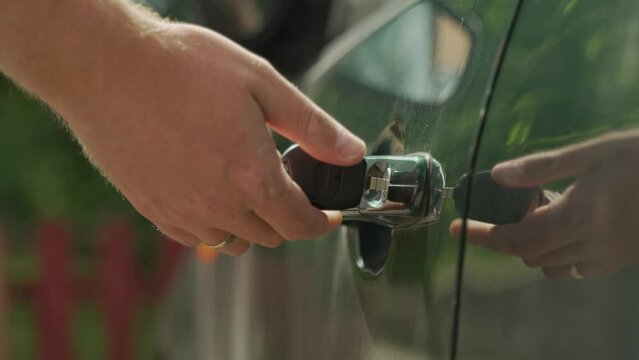 automotive theme
close-up of the keyhole of the central car lock of a green car
the owner man approaches the car and inserts the keys, turns them and opens the door
checking the alarm system 