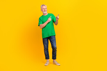 Full length photo of cool cheerful aged person look direct fingers empty space proposition isolated on yellow color background