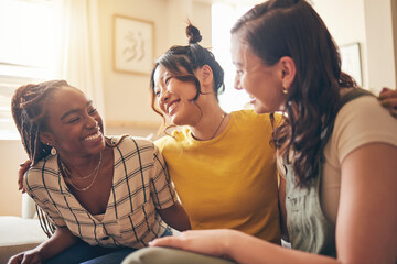 Happy, hug and women friends gossip, speaking and bond with care, trust and story in their home. Smile, embrace and people with diversity in a living room with support, conversation and social visit - Powered by Adobe