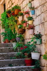Fototapeta na wymiar Flowers in pots suspended from an antique stone wall