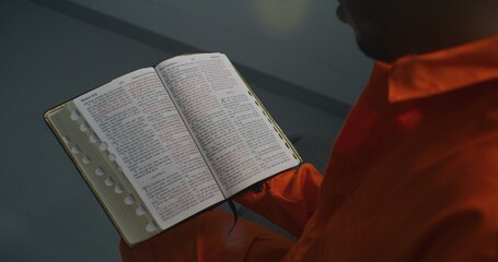 Close up shot of Bible. African American prisoner holds book in hand, reads, flips through pages....