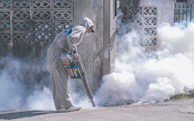 Healthcare worker using fogging machine spraying chemical to eliminate mosquitoes and prevent...