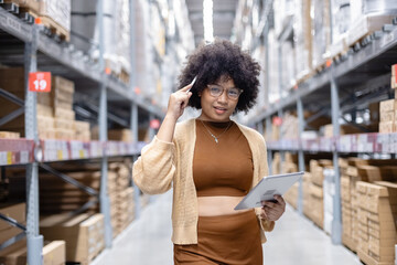 Young African American female looking at camera working in warehouse using digital tablet checking inspection on shelves.woman worker check stock inspecting in storage logistic factory.