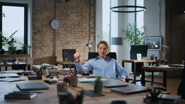 Sad business lady sitting in empty office. Woman playing with table pendulum