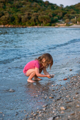 Little girl playing on the sea sandy beach