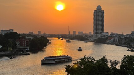 Aerial view of boat traffic on Chao Praya river with sunset, skyscrapers along Chao Praya river during sunset.