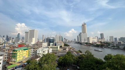 Obraz premium Skyscrapers along Chao Praya river, boat traffic on the river.