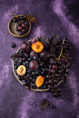 Assortment of purple fruit plum, grape, blueberry and basil