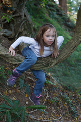 Little girl 7 years old on countryside. Kid climbing tree outdoor
