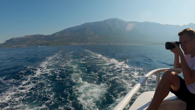 A guy photographs the seascapes of an island in the Adriatic Sea on the deck of a ship in Croatia. Boat trips to the nearby Paklin Islands in Croatia. People are sailing on a boat