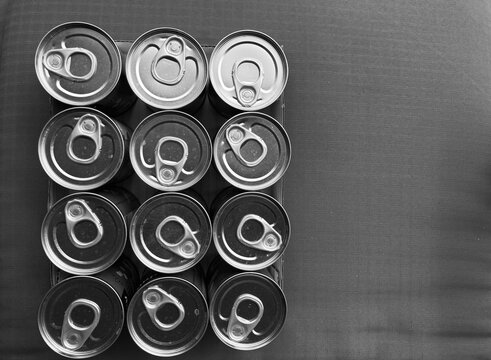arranged tin cans with opener from above in black and white