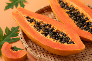 Fresh tropical cut papaya fruit over orange table background.