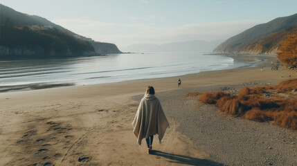 Smiling elderly woman in an oversized sweater walk on the seashore, a warm autumn day